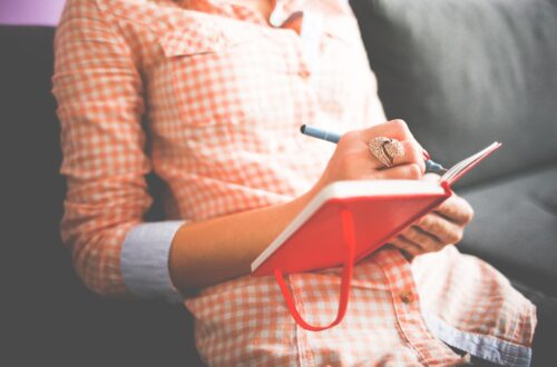 Collectable Quotes from Proverbs 29; A woman in a orange dress sits in a chair with a diary and a pen in her hand.
